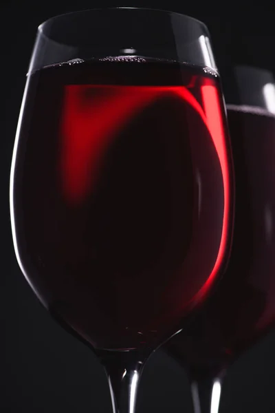 Gros plan des verres pleins de délicieux vin rouge sur noir — Photo de stock