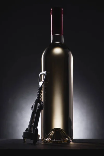 Close-up shot of bottle of white wine with corkscrew on black — Stock Photo