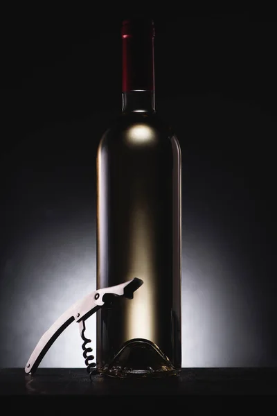 Primer plano de la botella de delicioso vino blanco en negro con sacacorchos - foto de stock