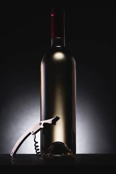 Close-up shot of bottle of delicious white wine on black with corkscrew — Stock Photo