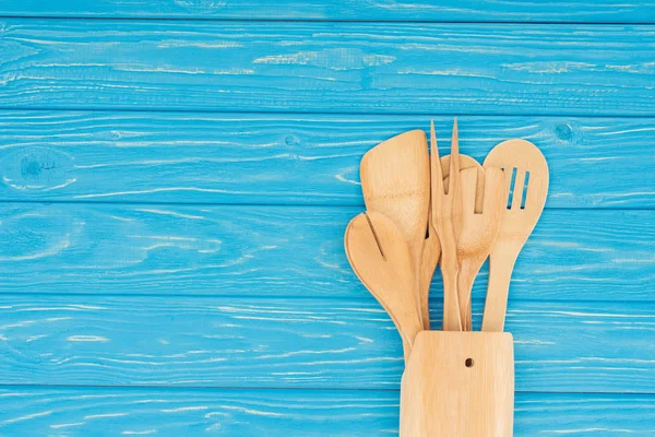 Vista superior de diferentes utensílios de cozinha de madeira na mesa azul — Fotografia de Stock