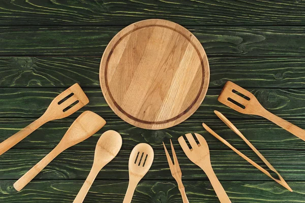 Vue du dessus de la planche à découper ronde et des ustensiles de cuisine en bois sur la table — Photo de stock