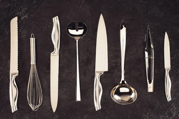 Vista superior de los utensilios de cocina colocados en fila sobre la mesa de mármol negro - foto de stock