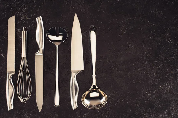 Vista sopraelevata di utensili da cucina disposti in fila su tavolo in marmo nero — Foto stock