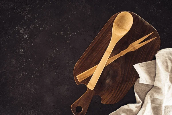 Top view of spoon, fork for meat on wooden cutting board and sackcloth on marble table — Stock Photo