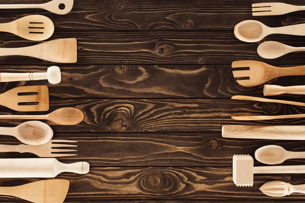 Повышенный вид на кухонную утварь, размещенную в два ряда на деревянном столе — стоковое фото