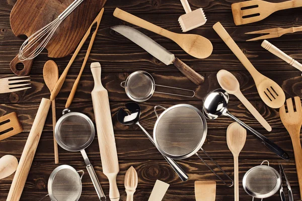 Vista elevada de diferentes utensilios de cocina sobre mesa de madera - foto de stock