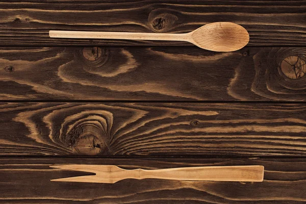 Vista elevada de garfo de madeira para carne e colher na mesa — Fotografia de Stock