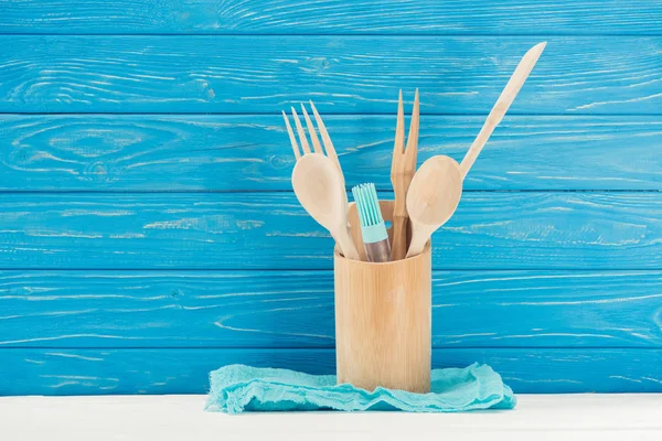 Крупный план тряпки, кисти для выпечки и кухонной утвари перед синей деревянной стеной — стоковое фото