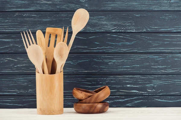 Vue rapprochée des ramequins et des ustensiles de cuisine devant le mur en bois — Photo de stock