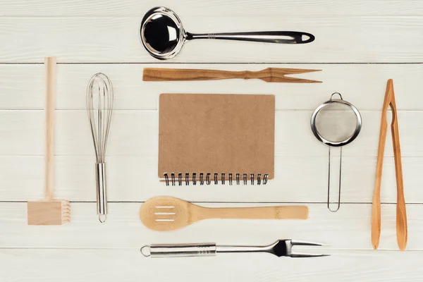 Vista elevata di libri di testo e utensili da cucina su tavolo in legno bianco — Foto stock