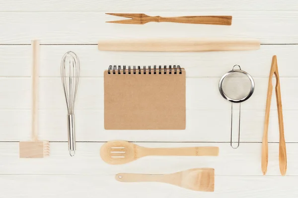 Vue du haut des manuels scolaires et des ustensiles de cuisine sur une table blanche en bois — Photo de stock