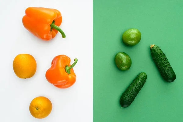 Вид зверху на апельсинові та зелені фрукти та овочі на білій та зеленій поверхні — стокове фото