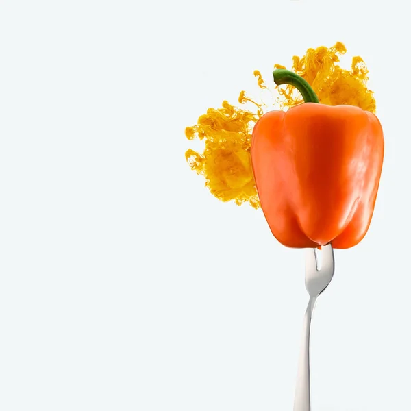 Orange bell pepper on fork and orange ink isolated on white — Stock Photo