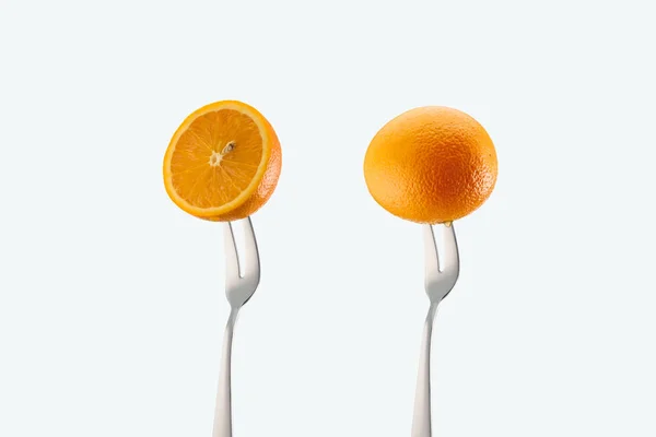 Cut and whole oranges on forks isolated on white — Stock Photo