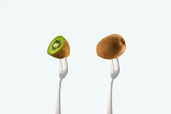 Corte y kiwis enteros en horquillas aisladas en blanco - foto de stock