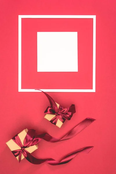 Top view of gift boxes with ribbons and frame with cube on red surface — Stock Photo