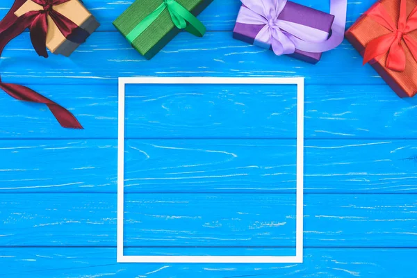 Vista dall'alto di scatole regalo e cornice vuota sul tavolo blu — Foto stock
