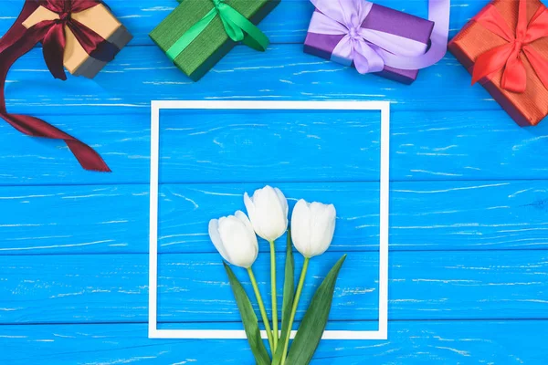 Ansicht von Geschenkboxen und weißen Tulpen im Rahmen auf blauem Tisch — Stockfoto