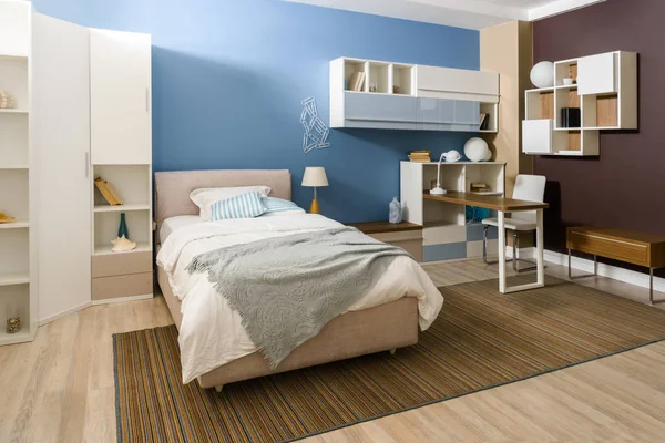 Ropa de cama en la cama en acogedor dormitorio en tonos azules - foto de stock