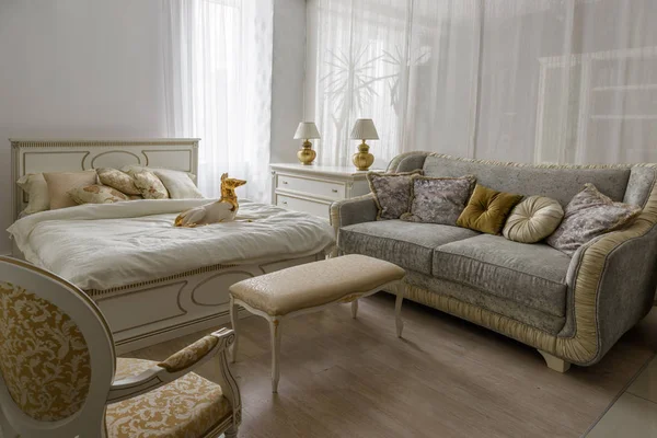 Статуэтка собаки на кровати с белым бельем в элегантной комнате — стоковое фото
