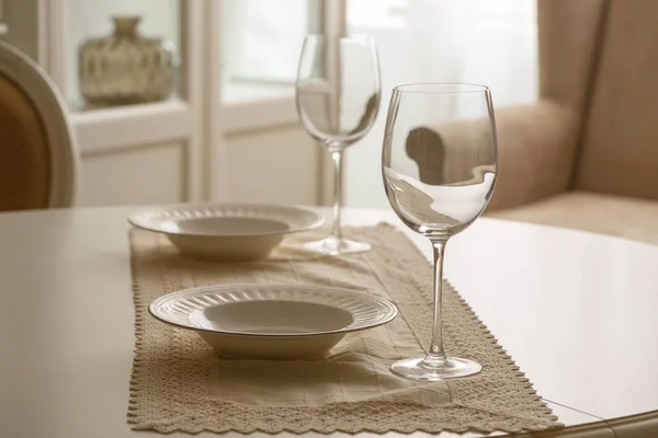 Бокалы и белые тарелки на столе в столовой — стоковое фото