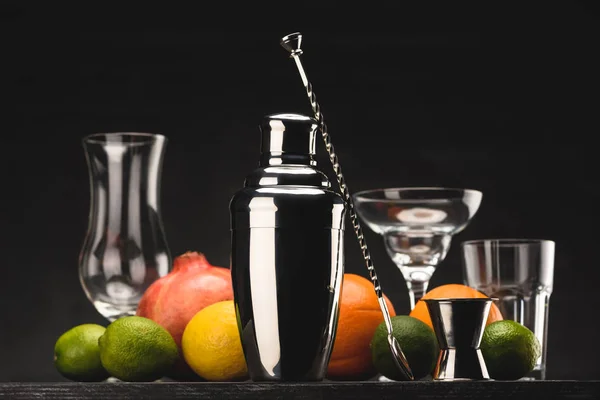Shaker for preparing alcohol drink and empty glasses on table isolated on black — Stock Photo