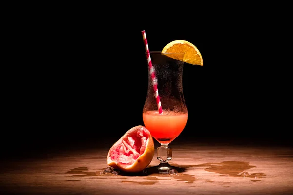 Alcohol cocktail with slice of orange and squeezed grapefruit on table — Stock Photo