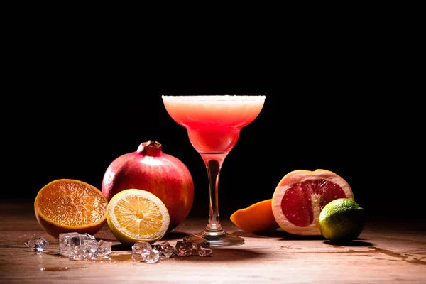 Bebida de alcohol rojo con frutas y cubitos de hielo en la mesa de madera - foto de stock