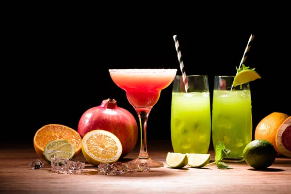 Bebidas alcoólicas com limão, romã e cubos de gelo na mesa — Fotografia de Stock