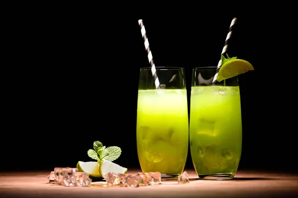 Alcohol mojito cocktails with lime and ice cubes on table — Stock Photo