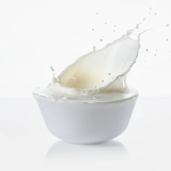 Milch spritzt in weißer Schüssel auf weißem Hintergrund — Stockfoto