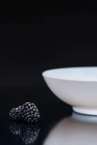 Mûres mûres mûres par bol blanc sur fond noir — Photo de stock