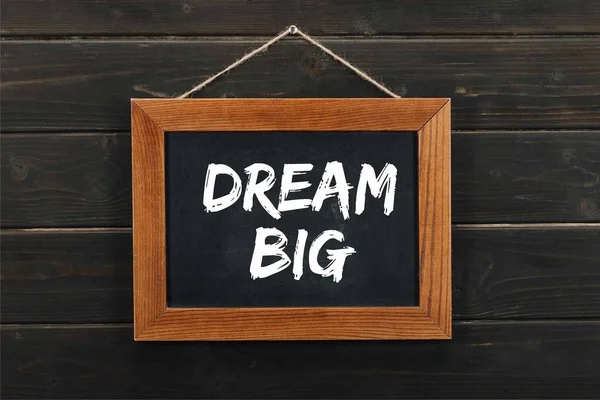Blackboard with dream big inscription hanging on wooden wall — Stock Photo