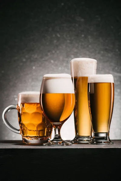 Vista de cerca de tazas dispuestas de cerveza sobre fondo gris - foto de stock