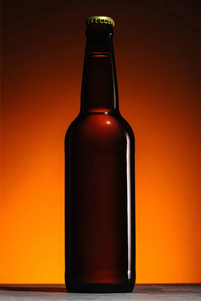 Vista de cerca de la botella de cerveza sobre fondo naranja - foto de stock