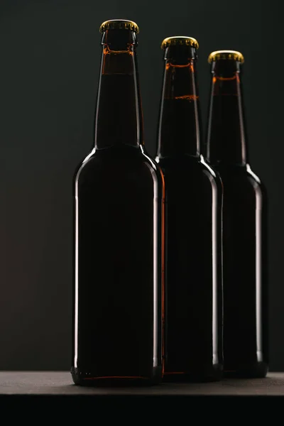 Vista de cerca de botellas dispuestas de cerveza sobre fondo oscuro - foto de stock