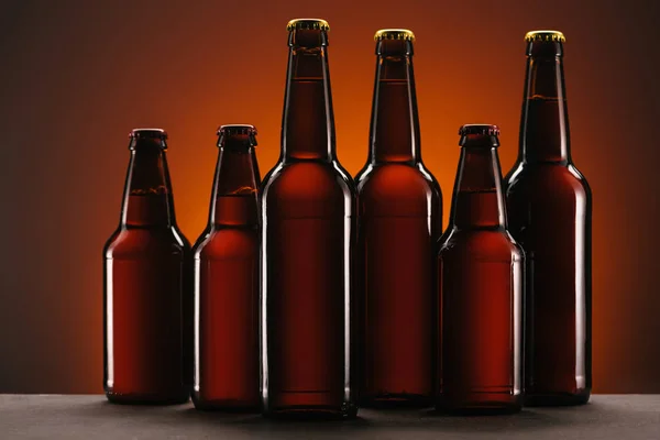 Vista de cerca de botellas arregladas de cerveza sobre fondo naranja - foto de stock