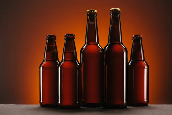 Close up view of arranged bottles of beer on orange backdrop — Stock Photo