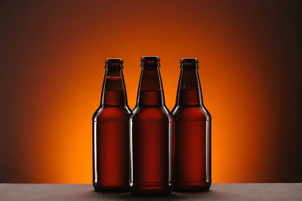 Close up view of arranged bottles of beer on orange backdrop — Stock Photo