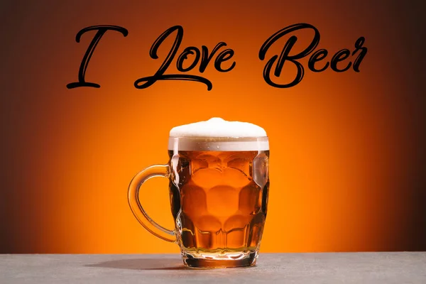 Close up view of mug of cold beer and i love beer lettering on orange backdrop — Stock Photo