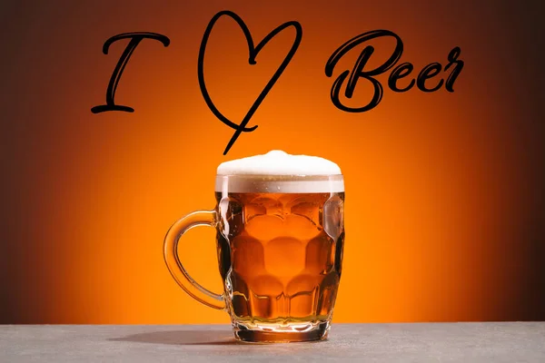 Primer plano vista de taza de cerveza fría y me encanta letras de cerveza sobre fondo naranja - foto de stock