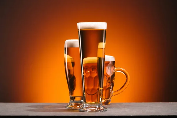 Close up view of arrangement of glasses of beer on orange backdrop — Stock Photo