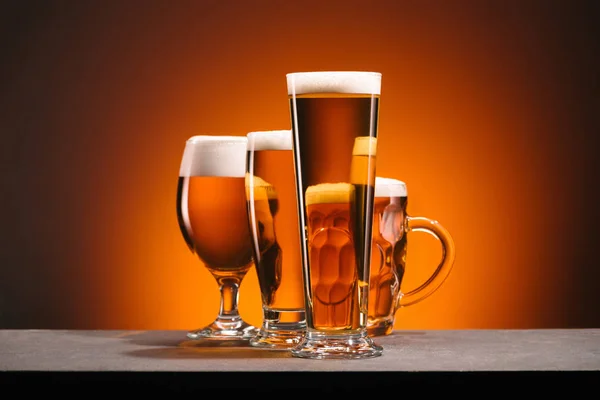 Close up view of arrangement of glasses of beer on orange backdrop — Stock Photo