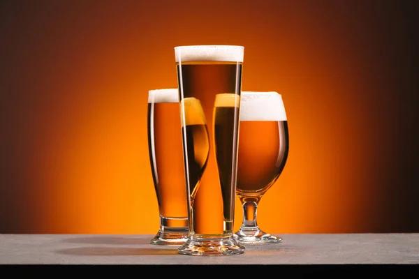 Vue rapprochée de l'agencement des verres de bière sur fond orange — Photo de stock