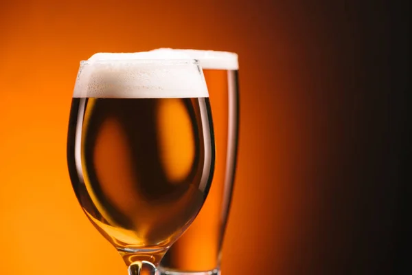 Close up view of arrangement of glasses of beer on orange backdrop — Stock Photo