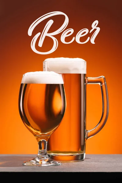 Vista de cerca de la disposición de vasos de cerveza y letras de cerveza sobre fondo naranja - foto de stock