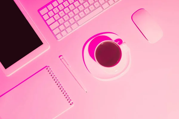 Foto tonificada rosa de xícara de café, tablet digital, caneta, livro didático, teclado de computador e mouse na mesa — Fotografia de Stock