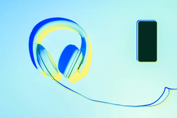 Image tonique bleue du smartphone avec écouteurs sur fond bleu — Photo de stock
