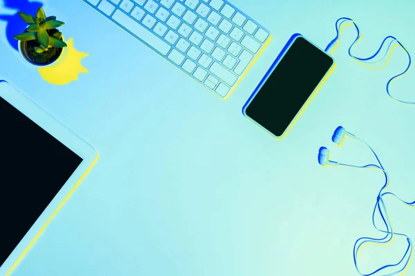 Голубая тонированная фотография смартфона, наушников, компьютерной клавиатуры, планшета — стоковое фото